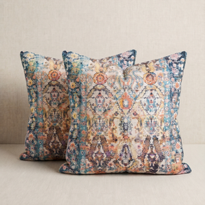 Two square decorative throw pillows with a distressed, ornate damask pattern in muted blue, beige, orange, and brown tones, displayed against a neutral beige background.